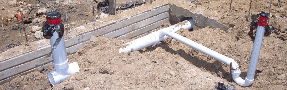 Nieuw aangelegde, witte, PVC buizen op een bouwplaats.